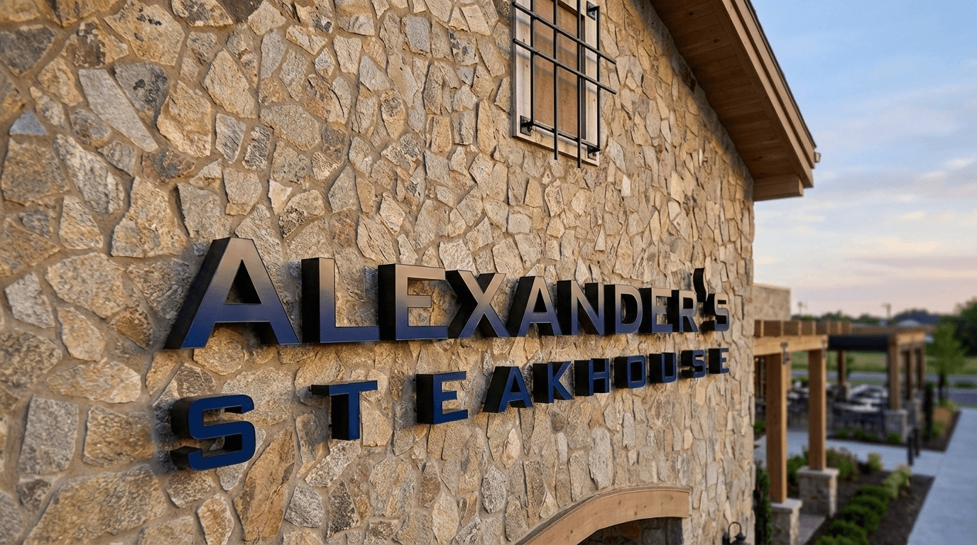 Alexander's Steakhouse logo in polished metal with warm LED lighting.