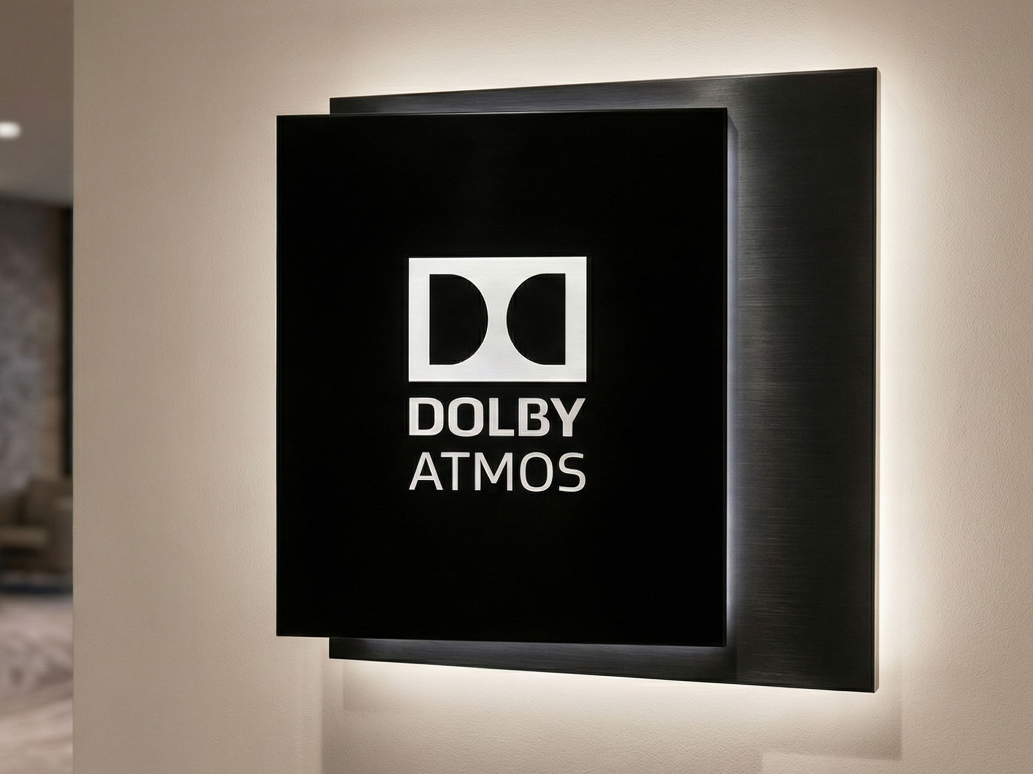 Backlit Dolby Atmos lobby sign with halo-lit letters on a dark feature wall
