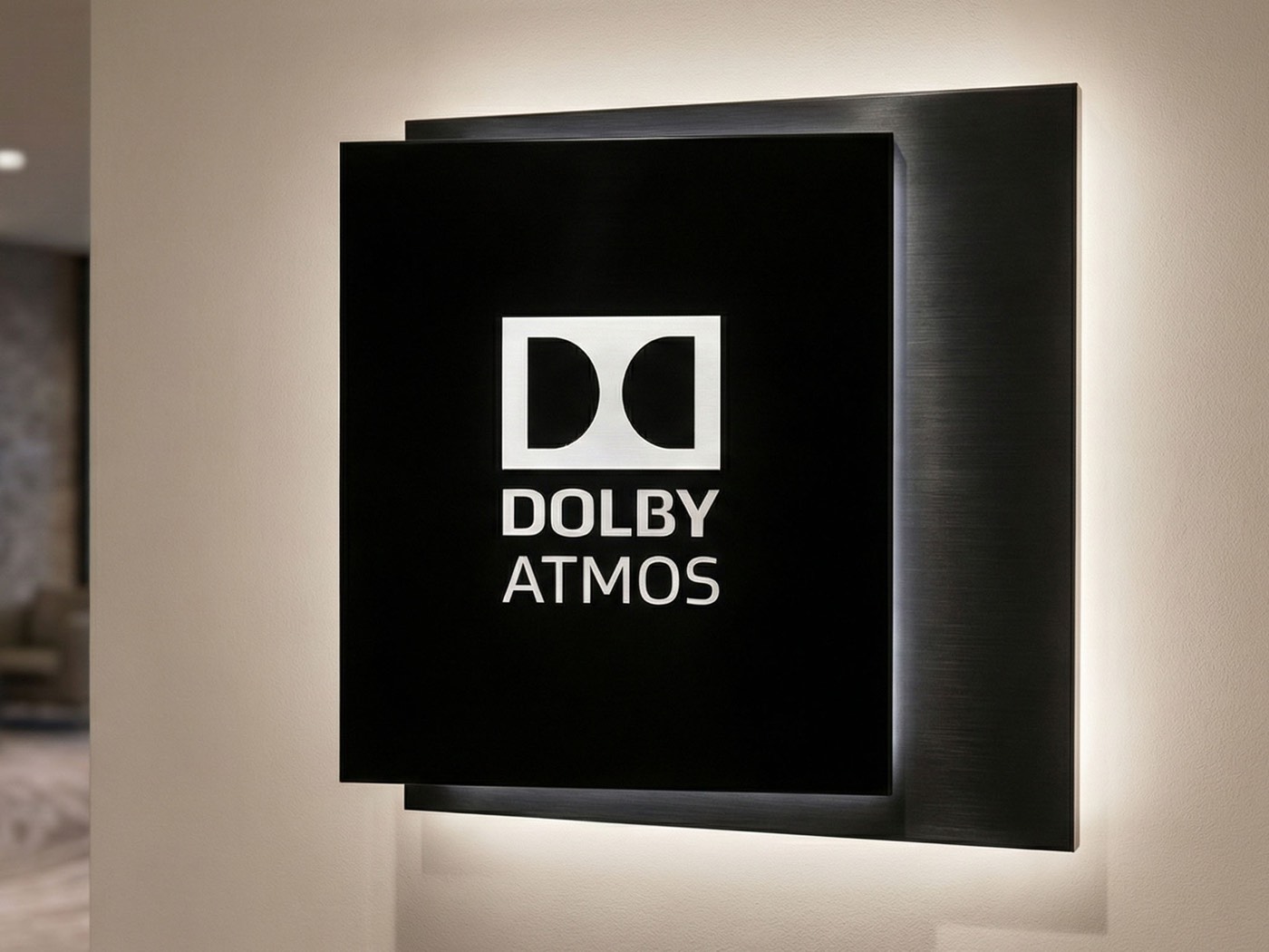 Backlit Dolby Atmos lobby sign with halo-lit letters on a dark feature wall