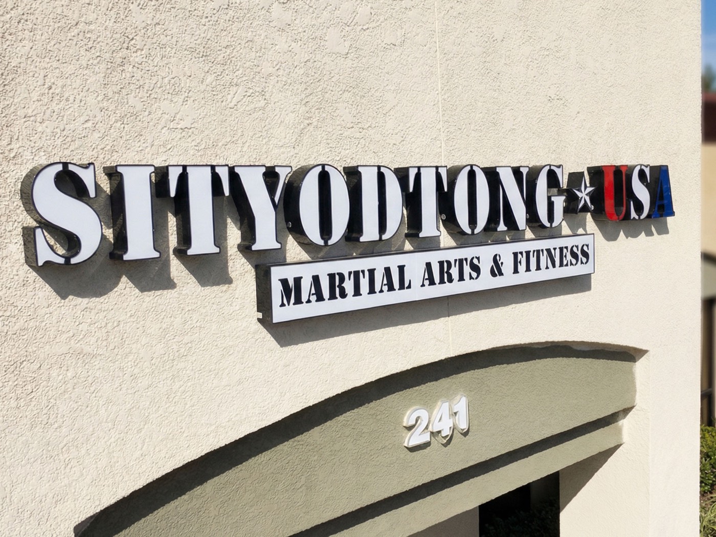 Illuminated exterior channel letters on a stucco facade for a martial arts business